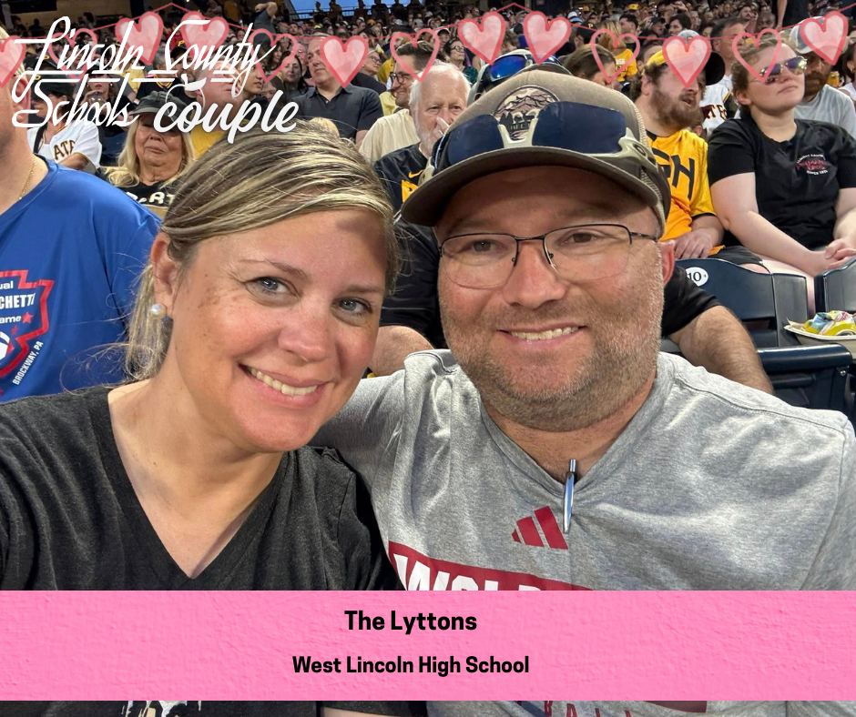 A smiling couple takes a close-up selfie while seated in crowded stadium bleachers, with many spectators visible behind them wearing black and gold. The person on the right wears a baseball cap and glasses, and the person on the left has light hair pulled back. Across the top of the image are heart graphics and the text “Lincoln County Schools couple.” A pink banner at the bottom reads “The Lyttons” and “West Lincoln High School.”