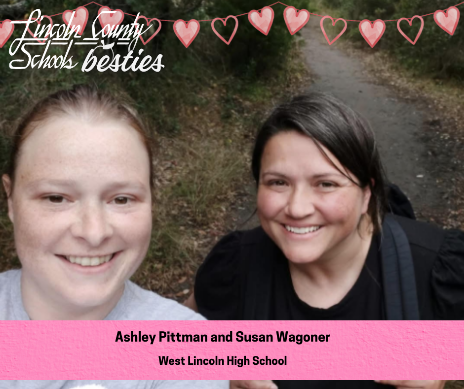 Two adults smile in a selfie taken outdoors on a narrow walking path surrounded by trees and grass. One person has light hair pulled back and wears a light-colored top, and the other has dark hair and wears a black top with backpack straps visible. Heart graphics and the text “Lincoln County Schools besties” appear across the top. A pink banner at the bottom reads “Ashley Pittman and Susan Wagoner” and “West Lincoln High School.”