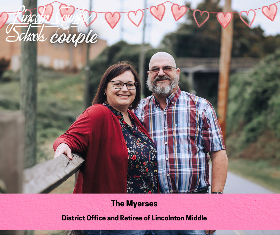 A couple stands side by side on a wooden walkway, smiling at the camera. The woman wears glasses, a red cardigan, and a floral top, resting one arm on the railing. The man has a gray beard and wears glasses and a short-sleeve plaid shirt. A string of illustrated heart garland and the words “Lincoln County Schools couple” appear at the top of the image. A pink banner at the bottom reads, “The Myerses — District Office and Retiree of Lincolnton Middle.”