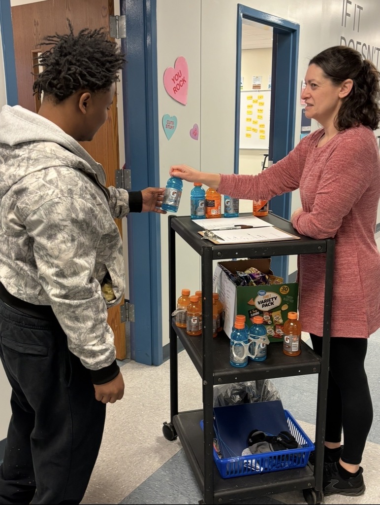 Teacher handing a student a sports drink as a prize.