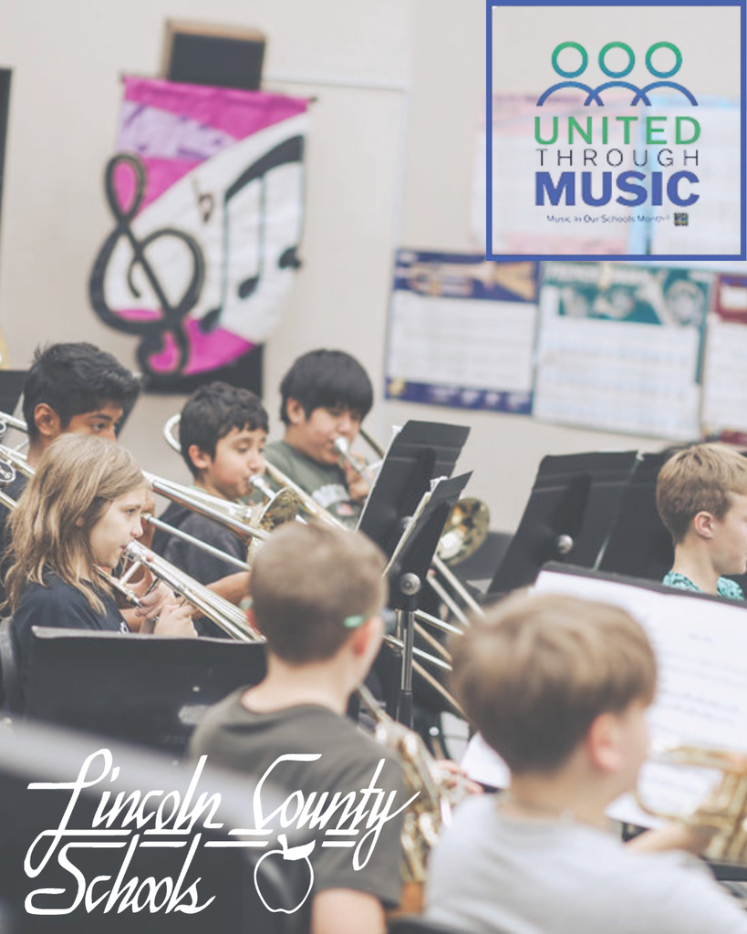 Students seated in a music classroom play brass instruments, including trombones and trumpets, while reading from black music stands. A colorful poster with a large treble clef and musical notes hangs on the wall in the background. In the top right corner, a graphic reads “United Through Music – Music In Our Schools Month.” The bottom of the image includes a Lincoln County Schools script logo.