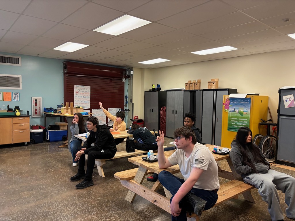 Students raising hands with questions for guest speaker.