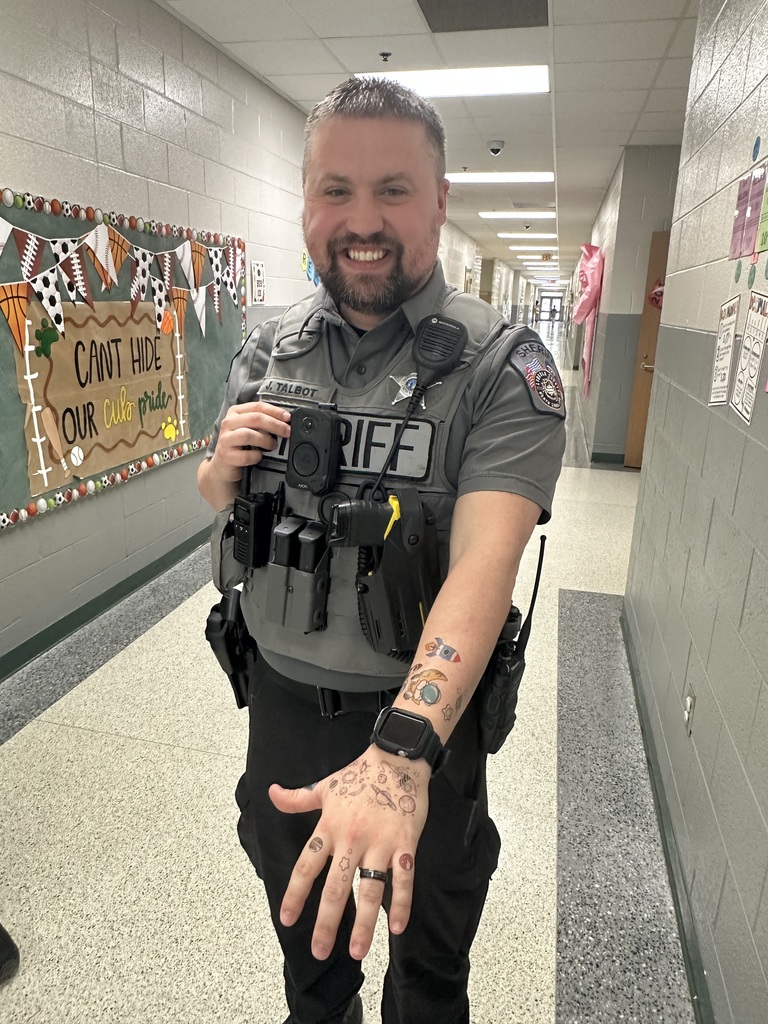Staff member proudly display colorful temporary tattoos on their arms during the 'Tattoo the Teacher' fundraiser.