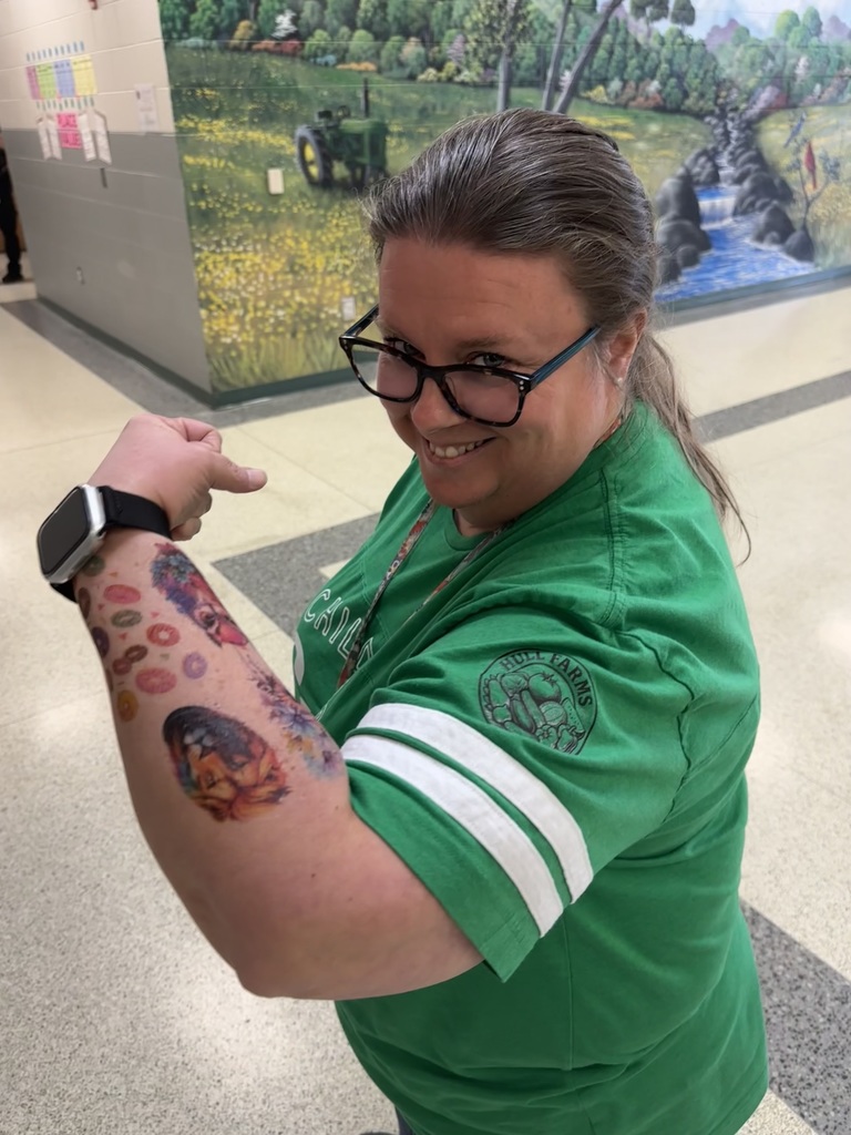 Staff member proudly display colorful temporary tattoos on their arms during the 'Tattoo the Teacher' fundraiser.