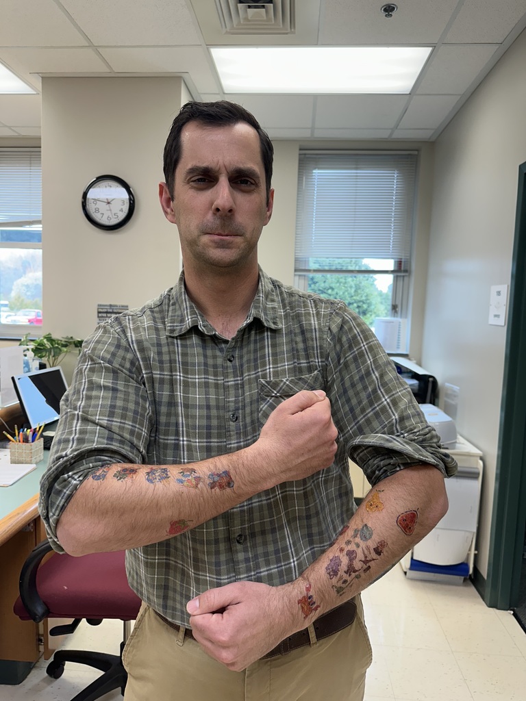 Staff member proudly display colorful temporary tattoos on their arms during the 'Tattoo the Teacher' fundraiser.
