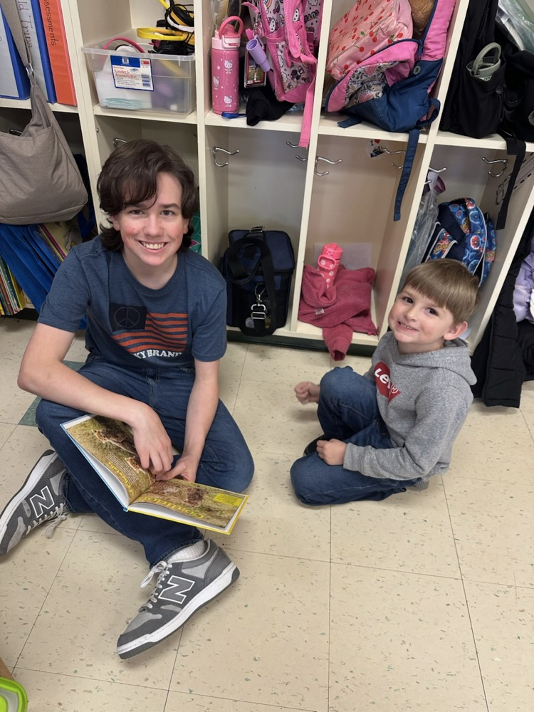 Middle School Student reading with a NCES student.