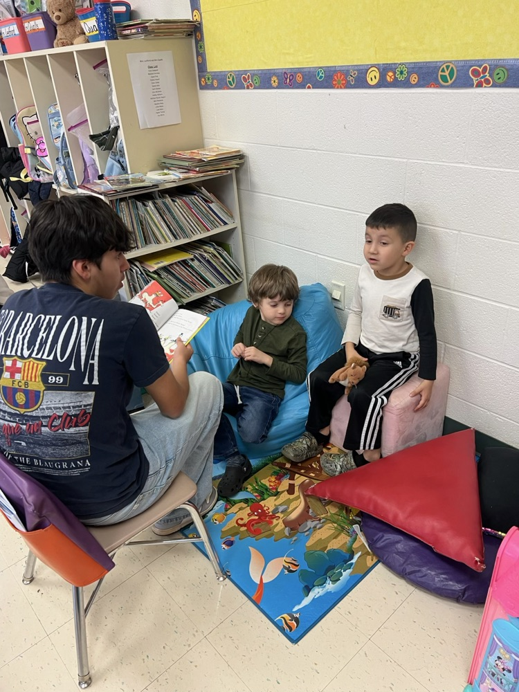 Middle School Student reading with NCES students.
