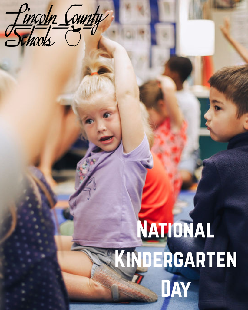A young kindergarten student sits on a classroom carpet with her hand raised while participating in a lesson. Other young students sit nearby and appear to be engaged in the activity. The Lincoln County Schools logo appears in the top left corner, and white text on the image reads “National Kindergarten Day.”