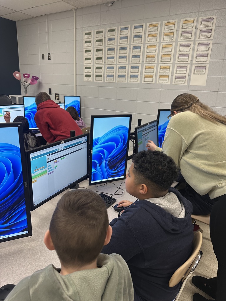 3rd grade students at the computers learning about coding from high school students.