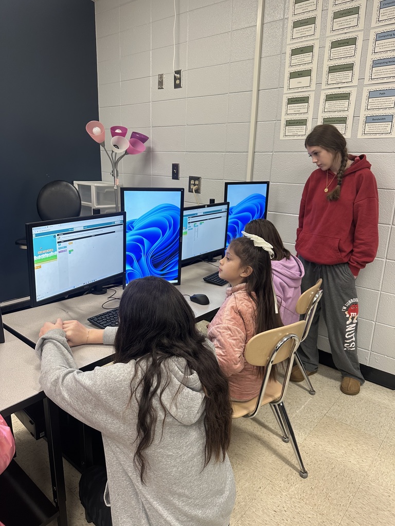 3rd grade students at the computers learning about coding from high school students.