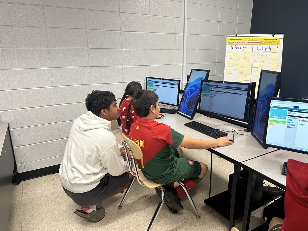 3rd grade students at the computers learning about coding from high school students.