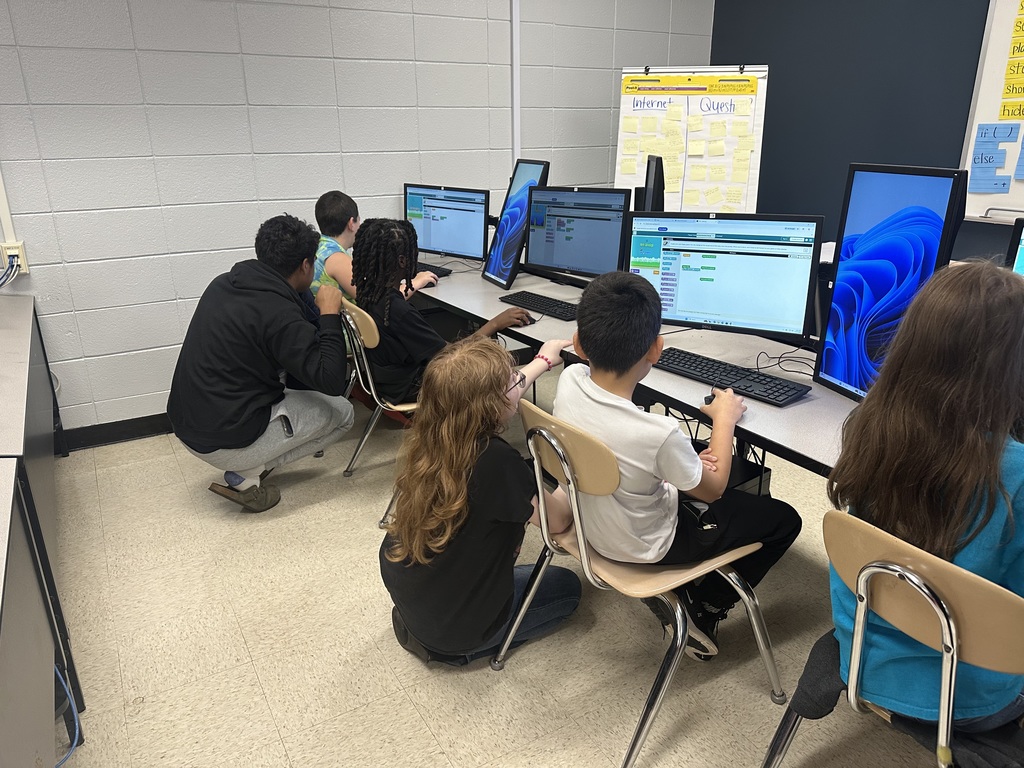 3rd grade students at the computers learning about coding from high school students.