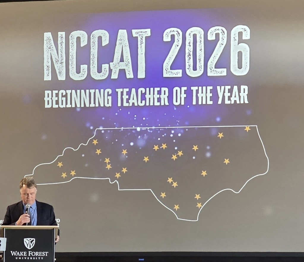 A projection screen reads “NCCAT 2026 Beginning Teacher of the Year” above a map of North Carolina marked with stars representing honorees. A speaker stands at a podium at the Wake Forest University venue during the ceremony.