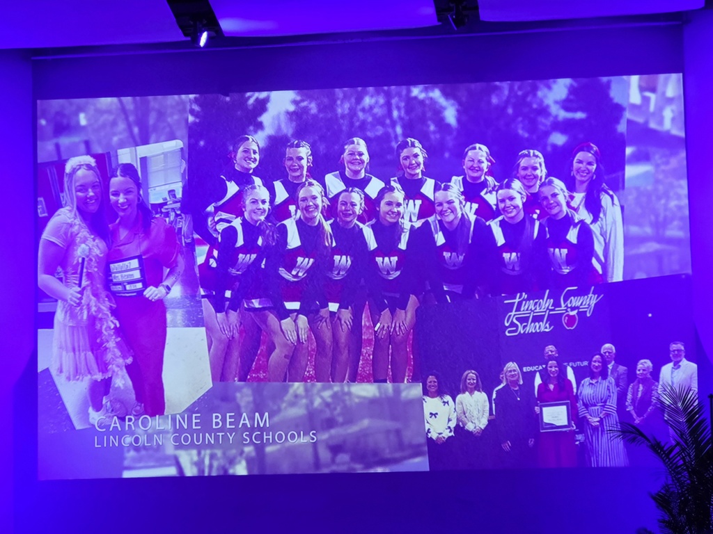 A large projection screen displays a collage of photos of Caroline Beam from Lincoln County Schools, including images of her with students and a cheer team. The name “Caroline Beam – Lincoln County Schools” appears on the screen during the ceremony.