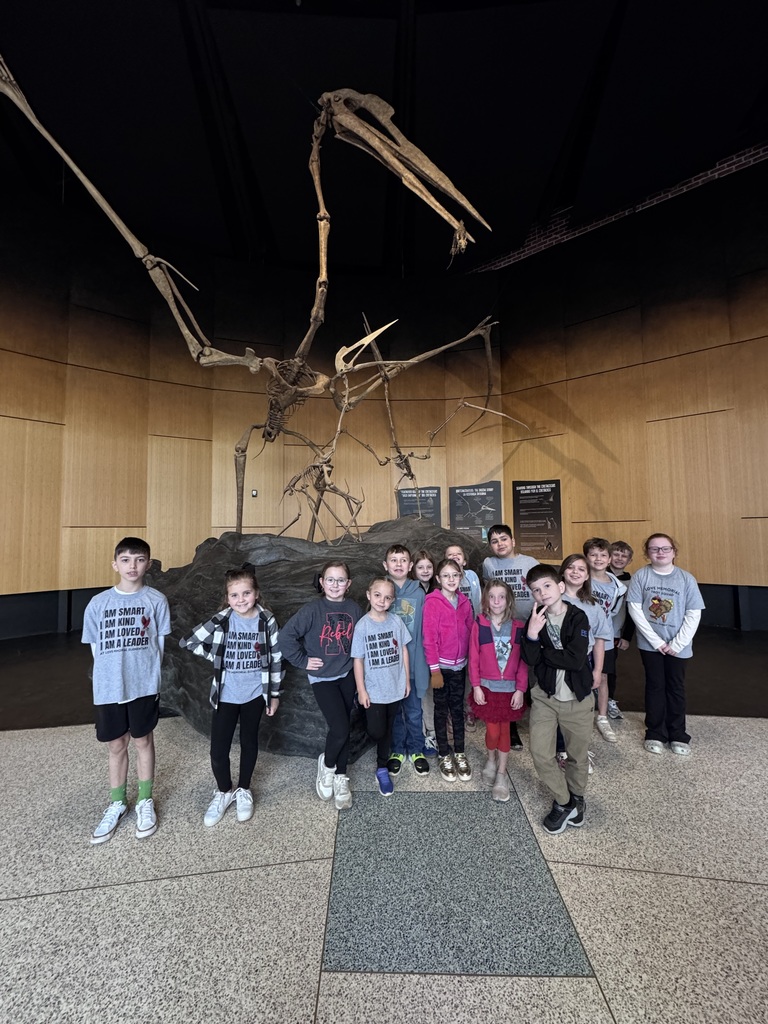 students at the museum posing with a dinosaur skeleton