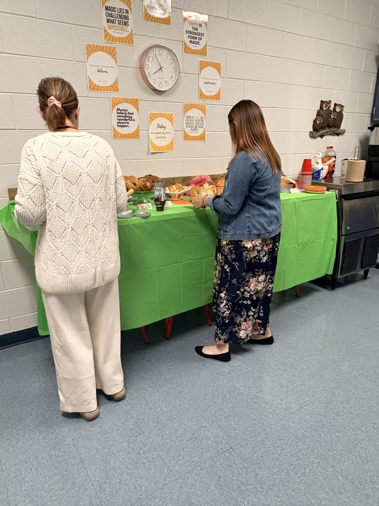 two teachers in a kitchen getting items off of a food bar