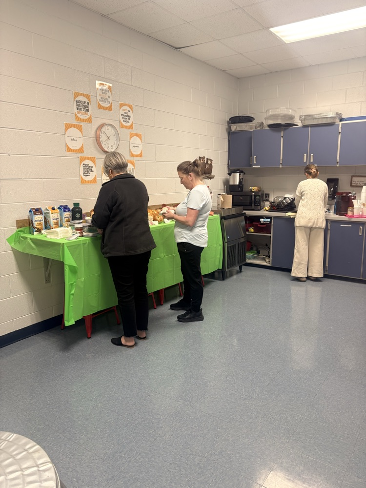 two teachers getting food items off of a food bar