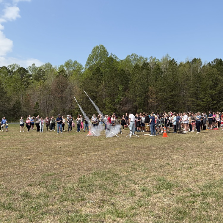 student and parents standing in the field for 5th grade rocket launch with star base