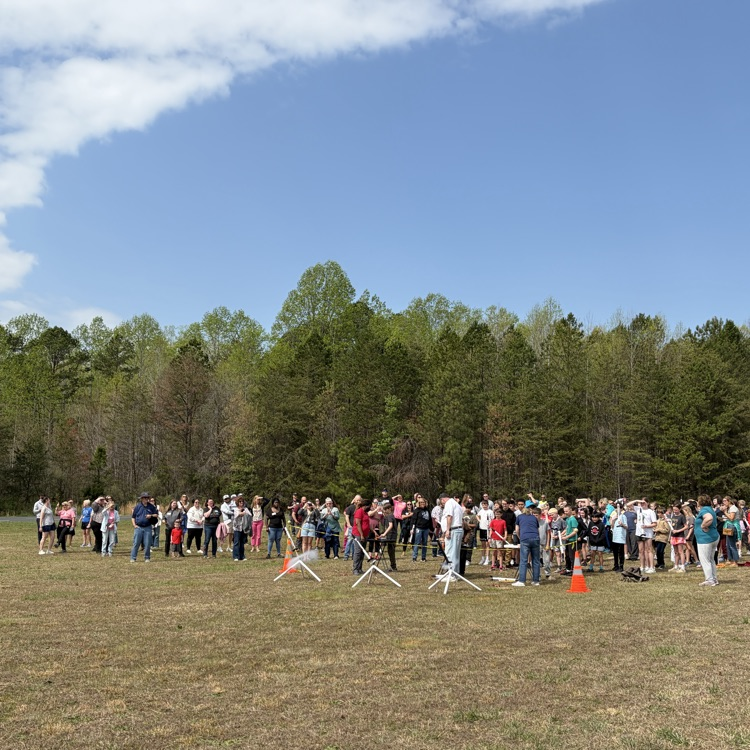 student and parents standing in the field for 5th grade rocket launch with star base