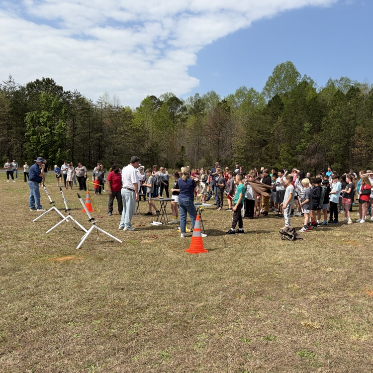 student and parents standing in the field for 5th grade rocket launch with star base