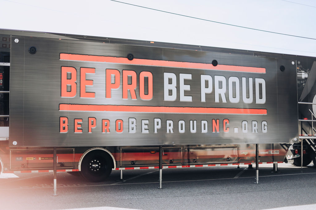 Black trailer with white and orange text. Text says "BE PRO BE PROUD" with a website below.