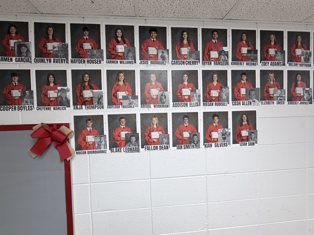 A white wall with many black-and-white photos of people in red shirts. A ribbon is tied to a whiteboard.