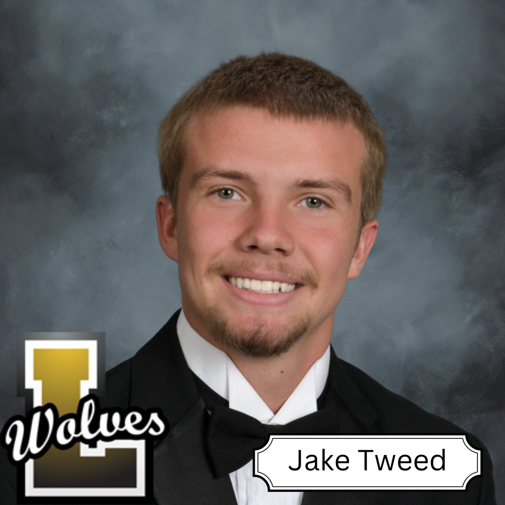 A man in a black suit and bow tie, smiling for a picture. Background is gray.