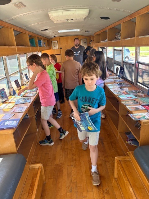student in blue shirt on book bus getting a book