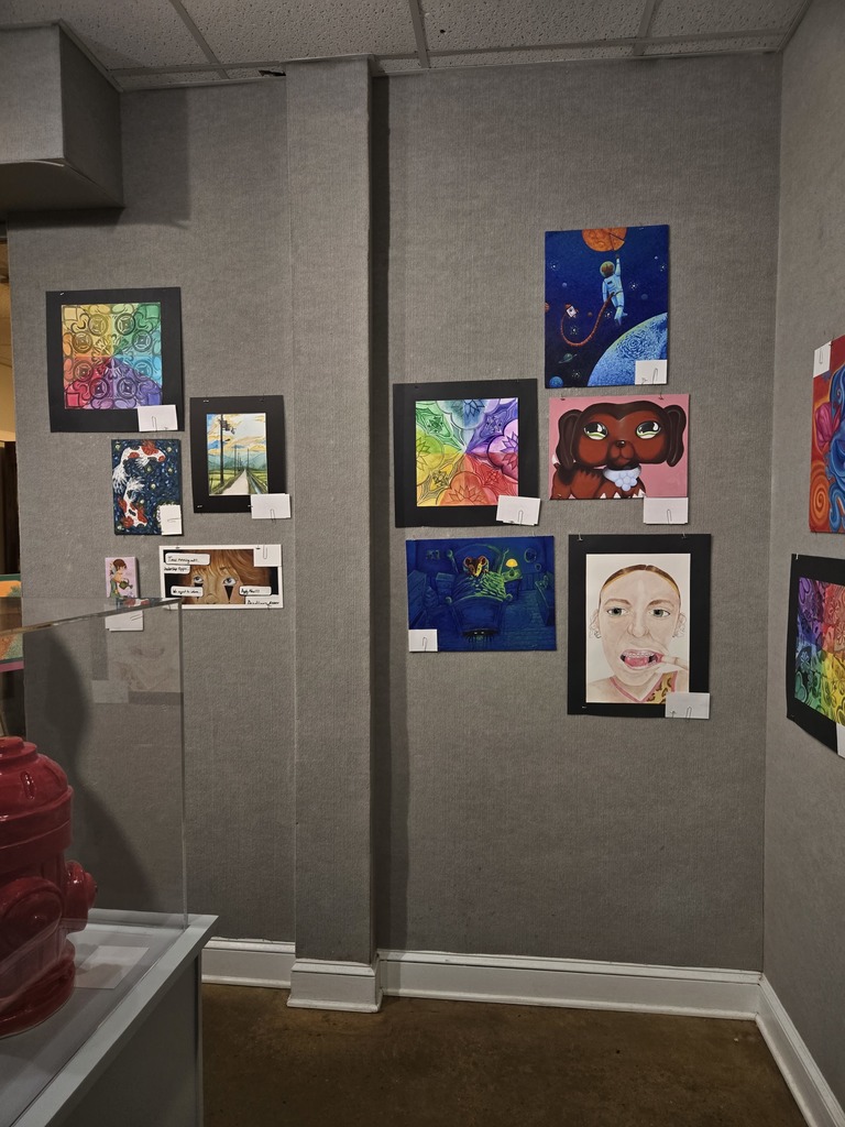 Photo of a wall with colorful paintings featuring  mandalas and portraits. 