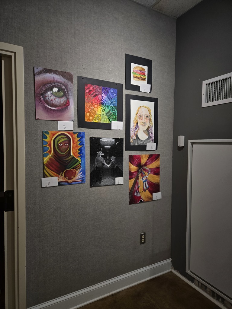 Photo of a wall with colorful paintings featuring an eye, a mandala, and portraits. 