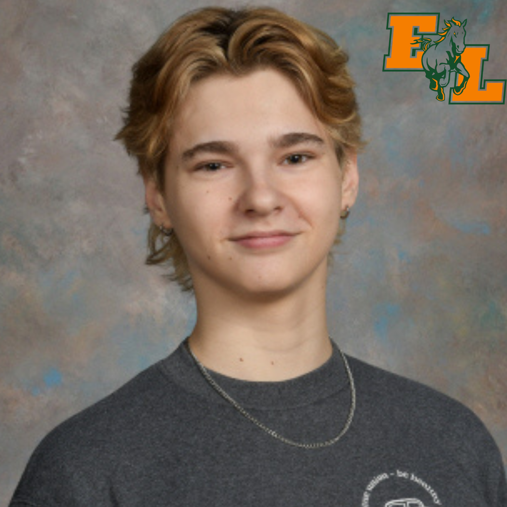 A boy with short blonde hair wearing a gray T-shirt and a silver necklace smiles against a blue background.