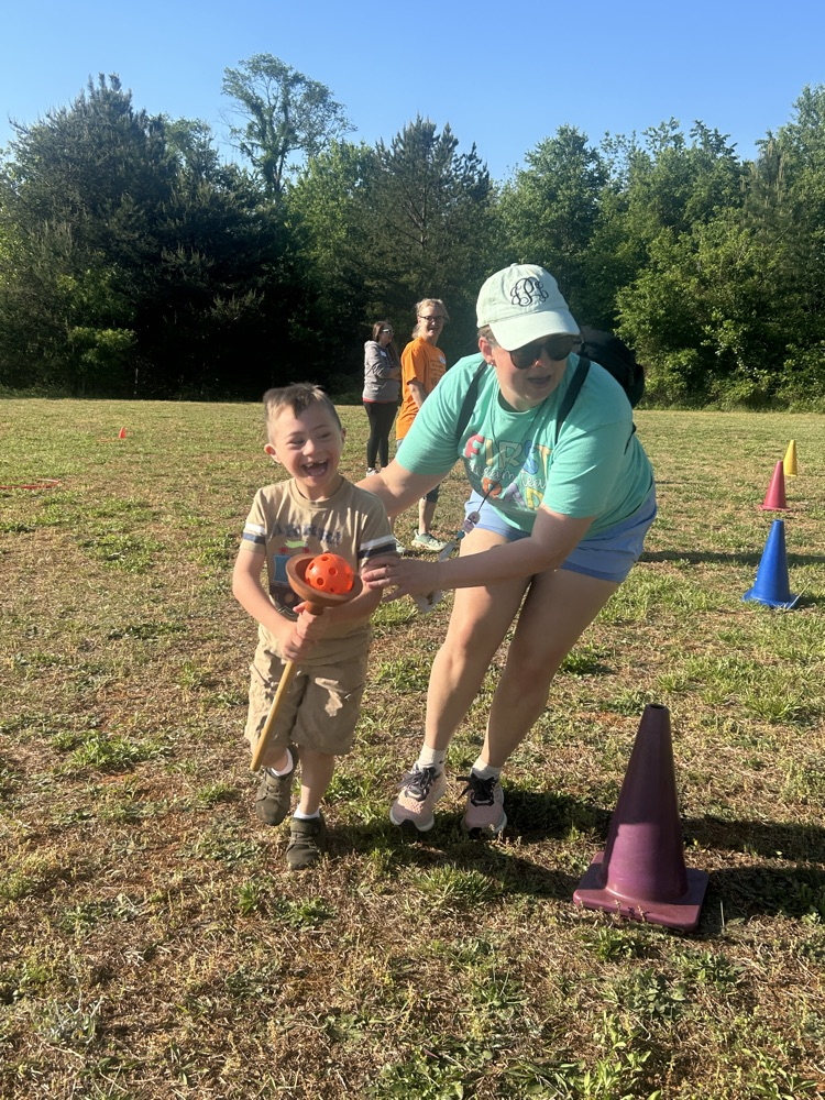student running with wiffleball with the help of an adult.
