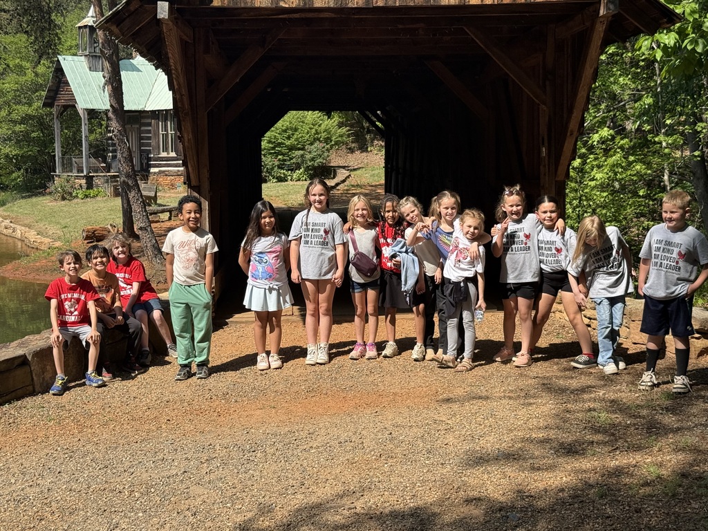 Group of children standing outside under a covered bridge on a gravel path.