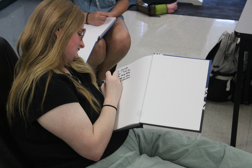 Yearbook students signing their yearbooks. 