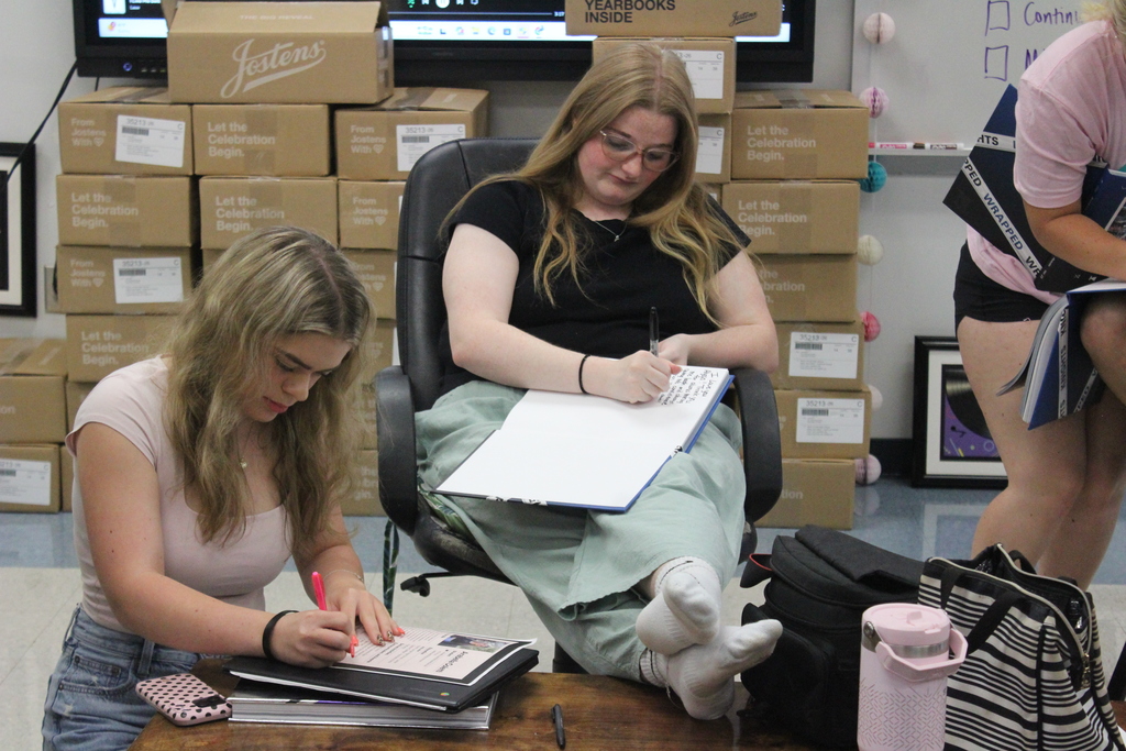 Yearbook students signing their yearbooks. 