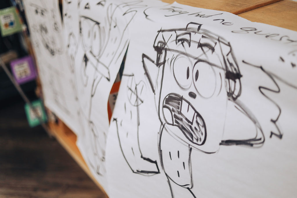 A white sheet with cartoon sketches of various characters. One character shows an angry expression with a wide open mouth.