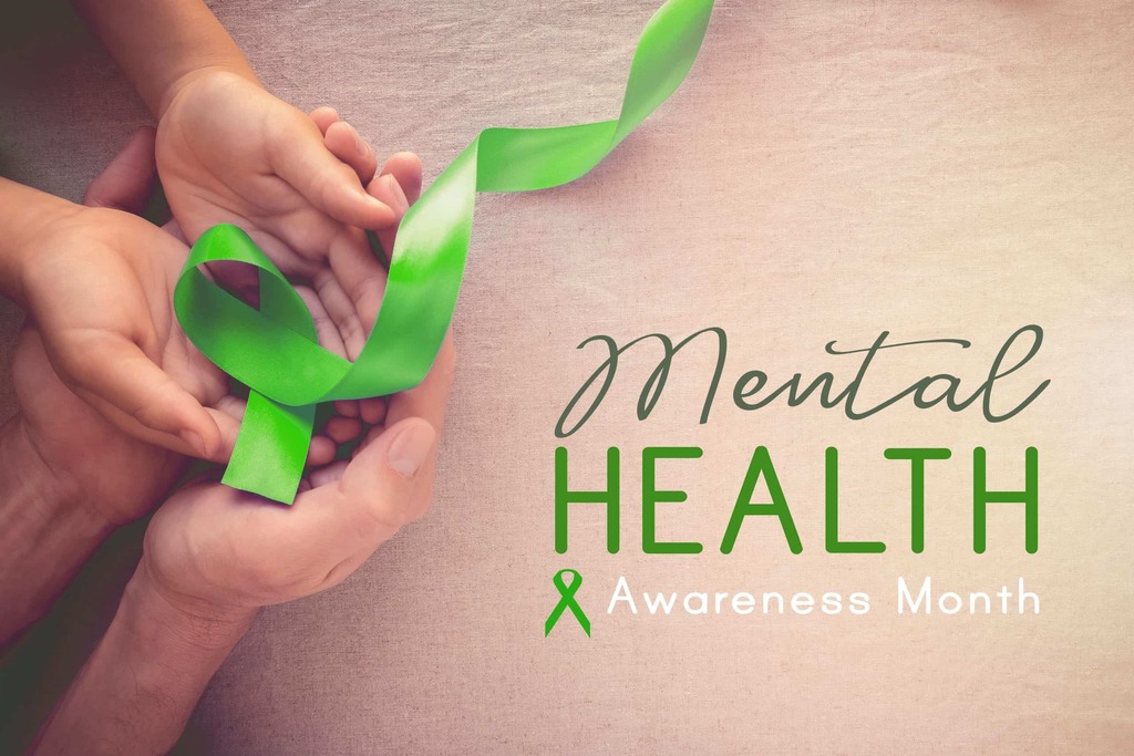Hands holding a green ribbon with "Mental Health Awareness Month" in bold letters on a beige background.