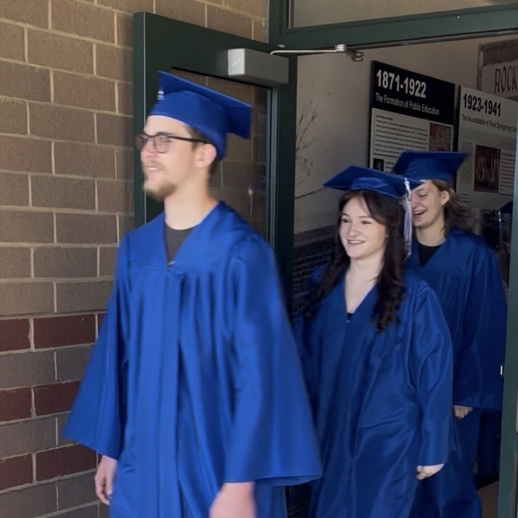 North Lincoln High School seniors coming out of front door of Rock Springs in graduation attire