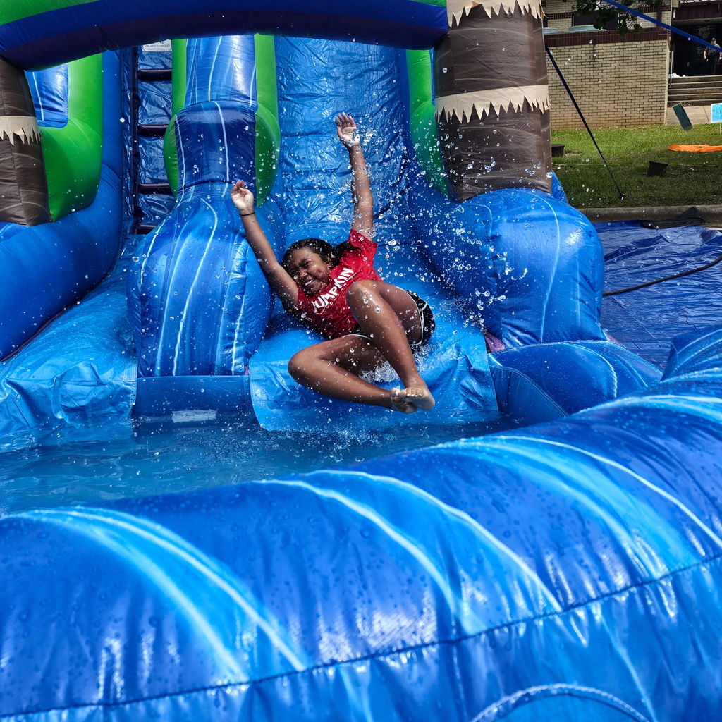 A person slides down a large, blue water slide with water splashing around them.