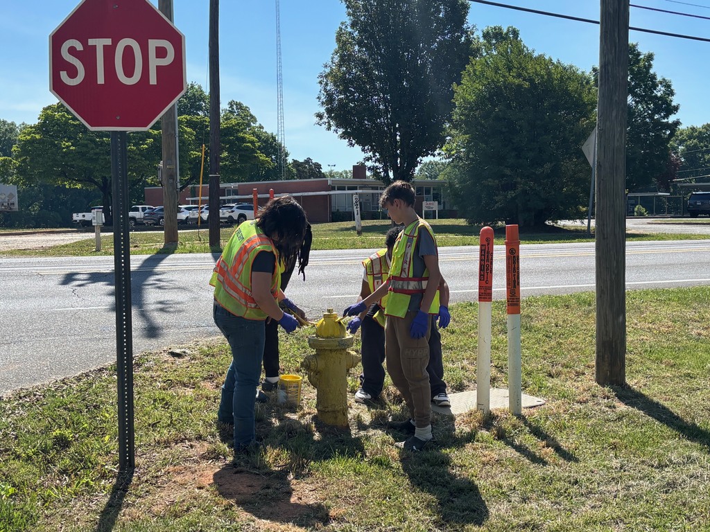 Four people in reflective vests next to a stop sign and a yellow fire hydrant.