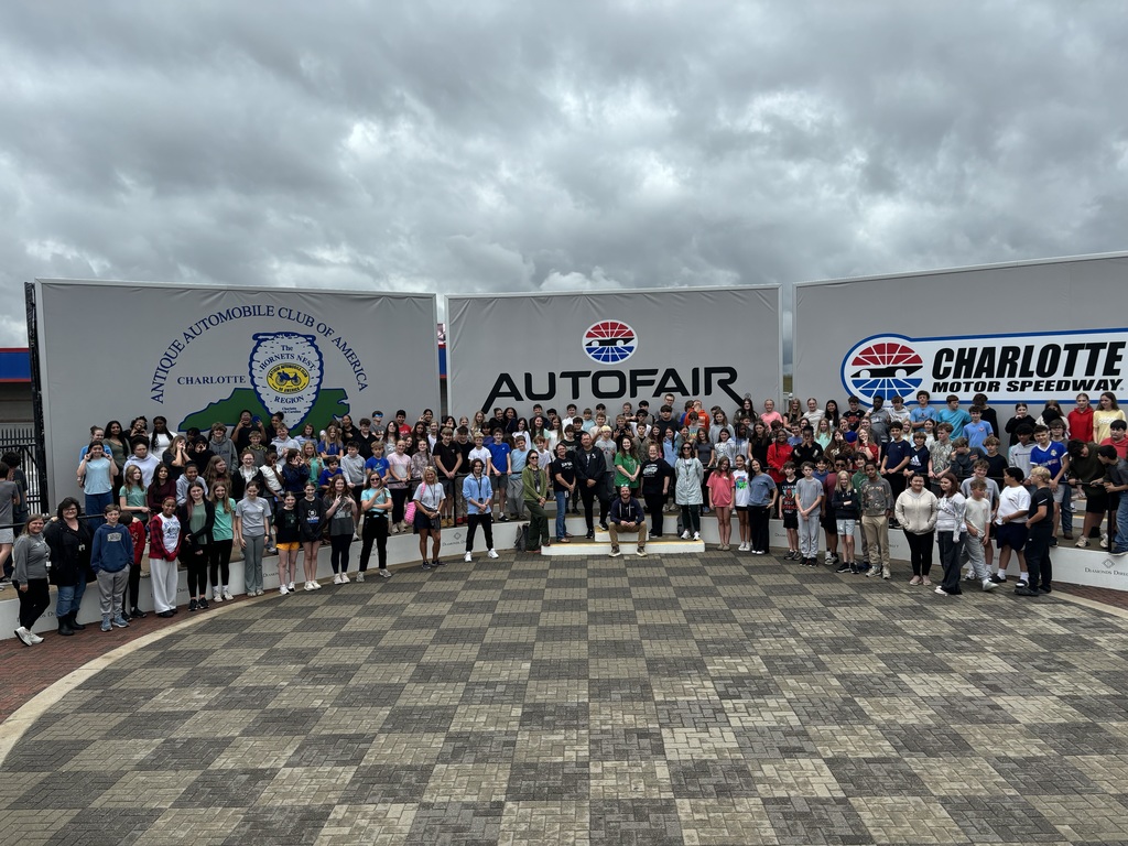 A large group of people stands in front of a white sign with the word "AUTOFAIR" on it.