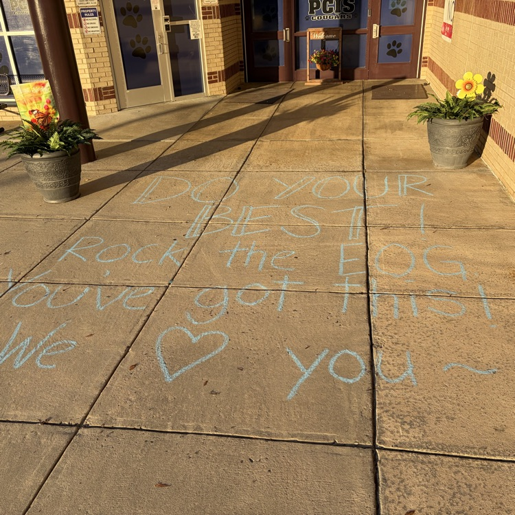 picture of the front of a school with chalk on the sidewalk saying “do your best, you’ve got this, rock this EOG we love you