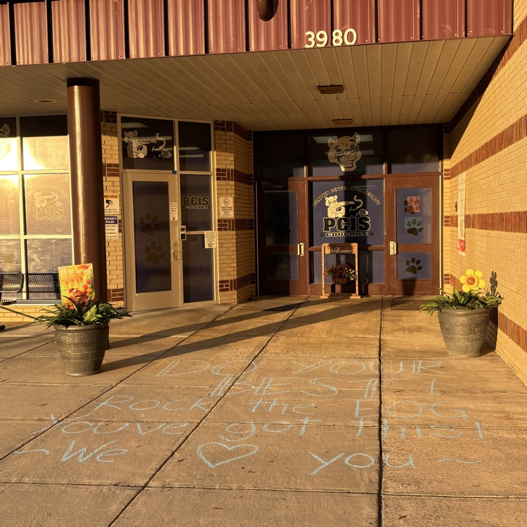picture of the front of a school with chalk on the sidewalk saying “do your best, you’ve got this, rock this EOG we love you