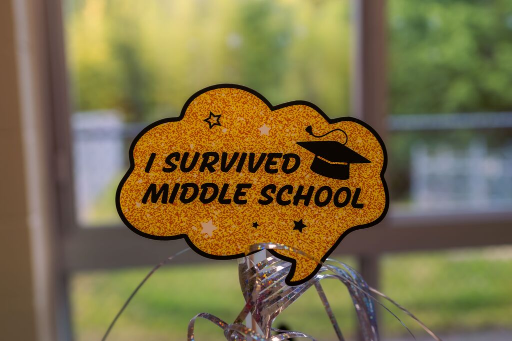 A yellow speech bubble with black text and stars reads "I SURVIVED MIDDLE SCHOOL" above a silver and gold tassel.