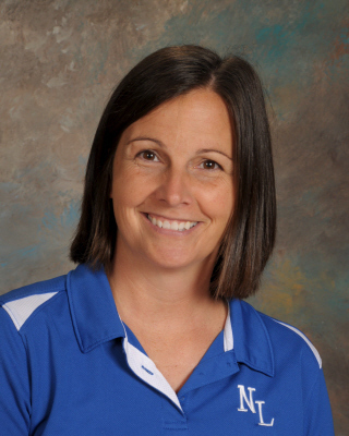 A smiling woman with short brown hair in a blue collared shirt with white trim and "NL" printed.