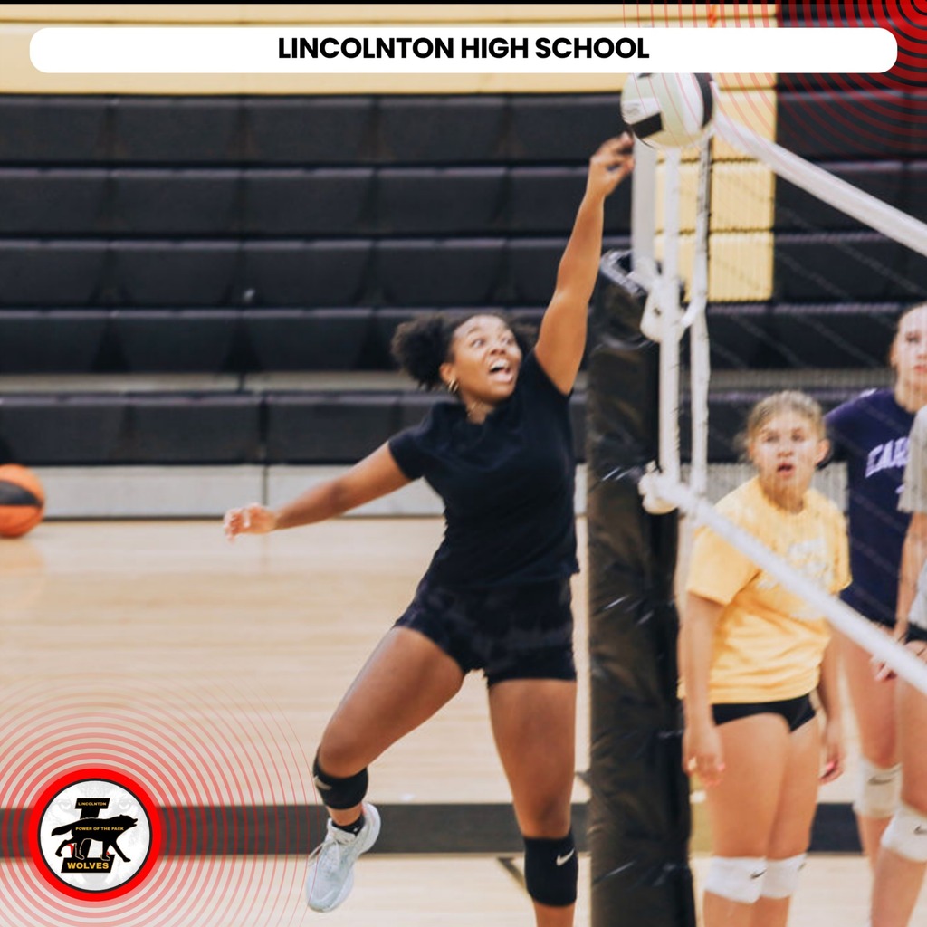 A female volleyball player in black uniform jumps and stretches her arm to hit the ball.