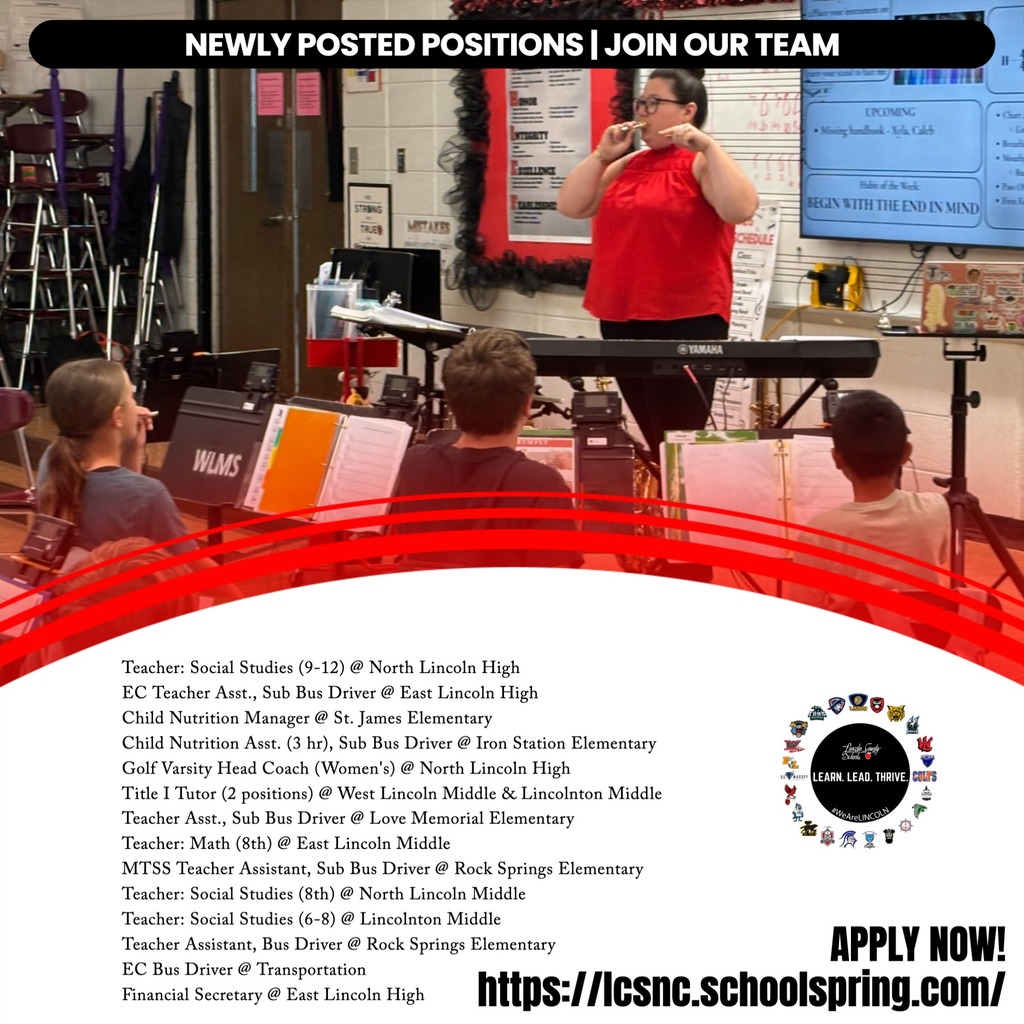 A music teacher in a red shirt stands before students in a classroom, with a piano and music sheets.
