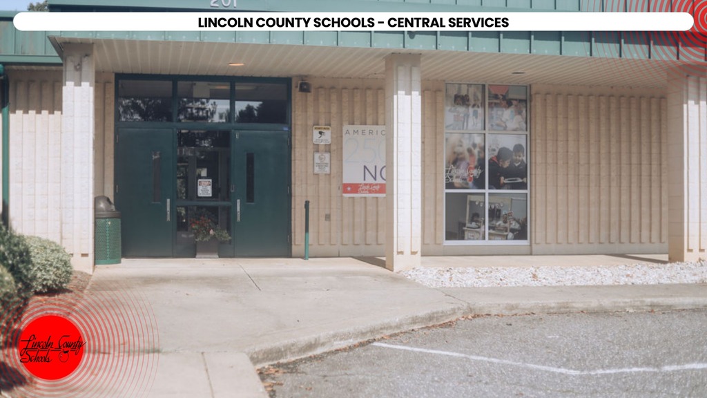 Building exterior with green door and large window displays; sign reads "Lincoln County Schools - Central Services."