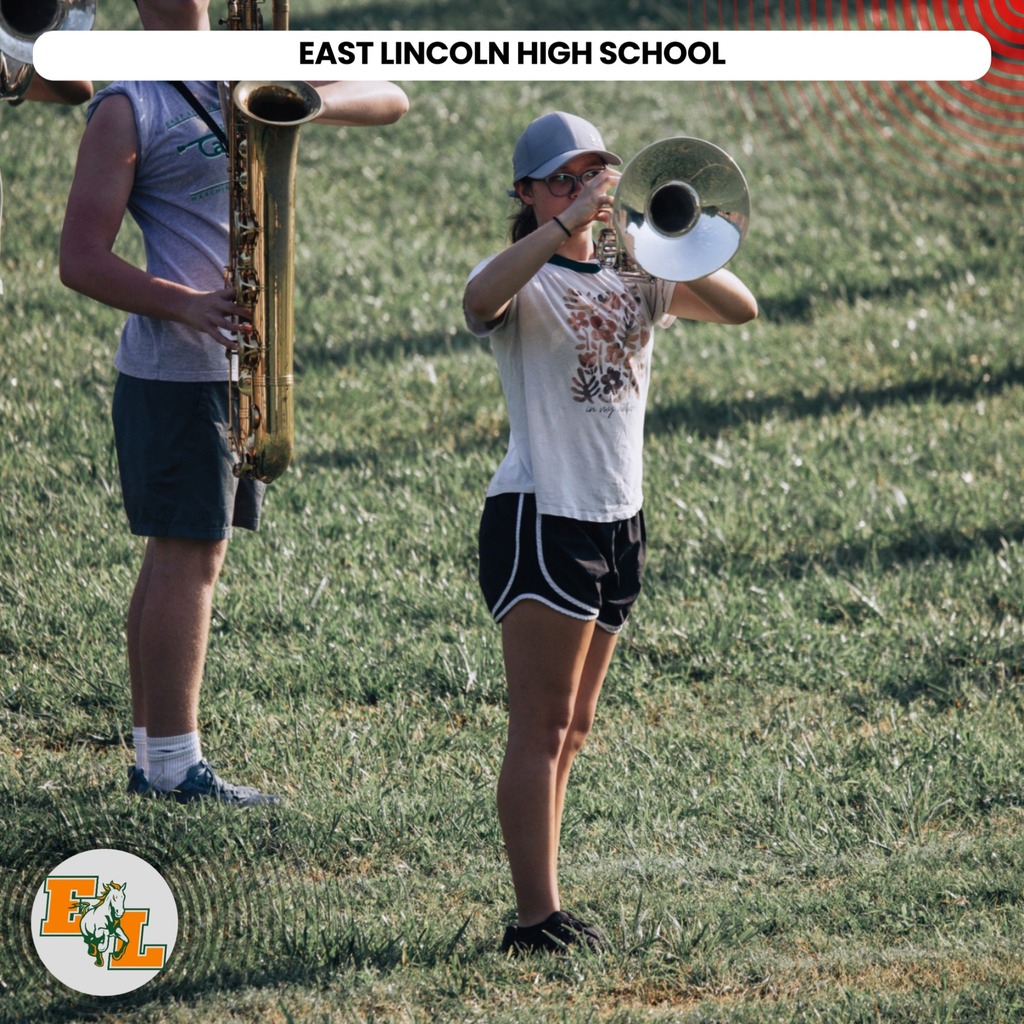 Two students at East Lincoln High School play musical instruments in a grassy area. One holds a trumpet, the other a saxophone.
