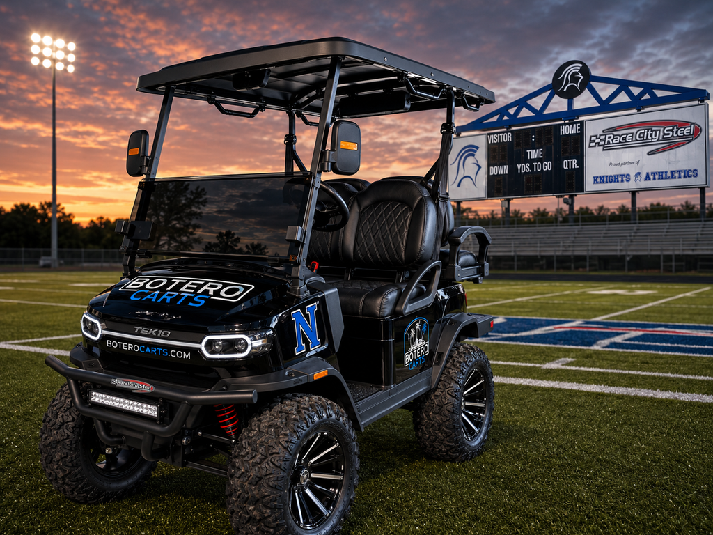 A black golf cart with "MOTOR CARS" and "N" on the side on a football field at sunset.